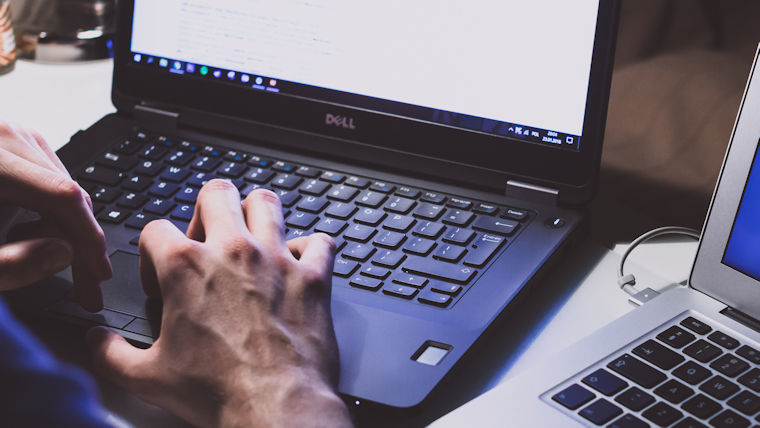 Photo of hand typing on a laptop keyboard